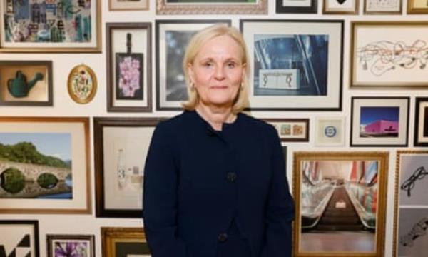 Amanda Blanc poses for a picture in front of a wall full of photos in f<em></em>rames