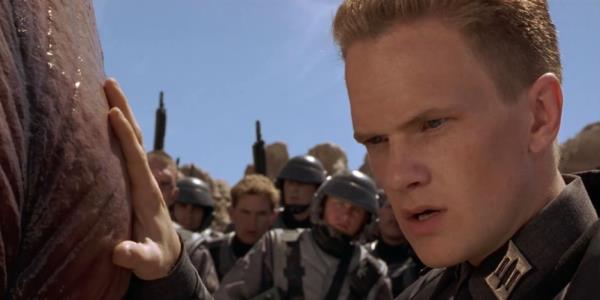 Two soldiers wearing armor firing big guns in Starship Troopers